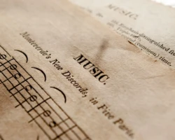 Photo Credit: Oleg Tischenkov Detailed view of antique music sheets featuring notes and Monteverde's New Discords in sepia tone.